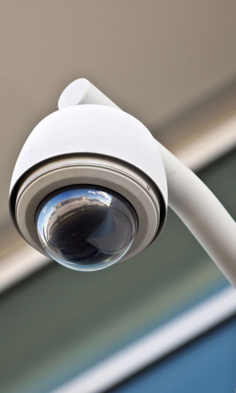 White surveillance camera with a reflection of a building